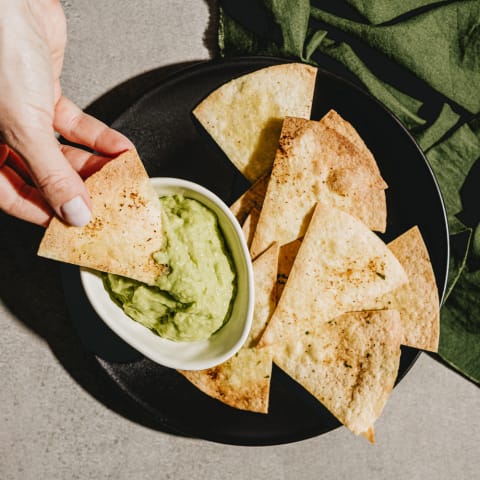 Hand Dipping Tortilla Chip into Guacamole