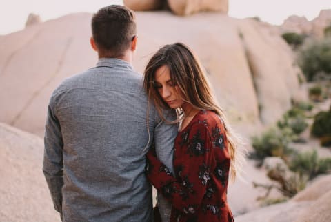 woman gripping a mans arm while he stands backwards