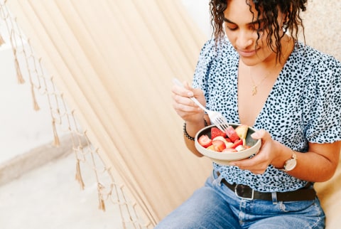 Woman Eating Fruit While Sitting In A Hammock