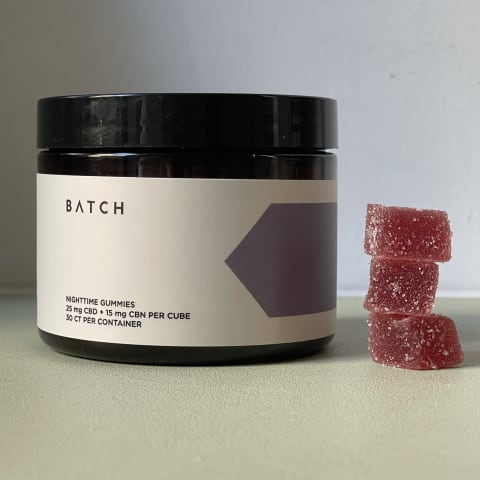 Batch Nighttime CBD Gummies for Sleep On Desk next to stack of three CBD gummies